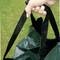 Hand hält eine grüne Tasche mit schwarzen Griffen. Hintergrund zeigt grünen Rasen.