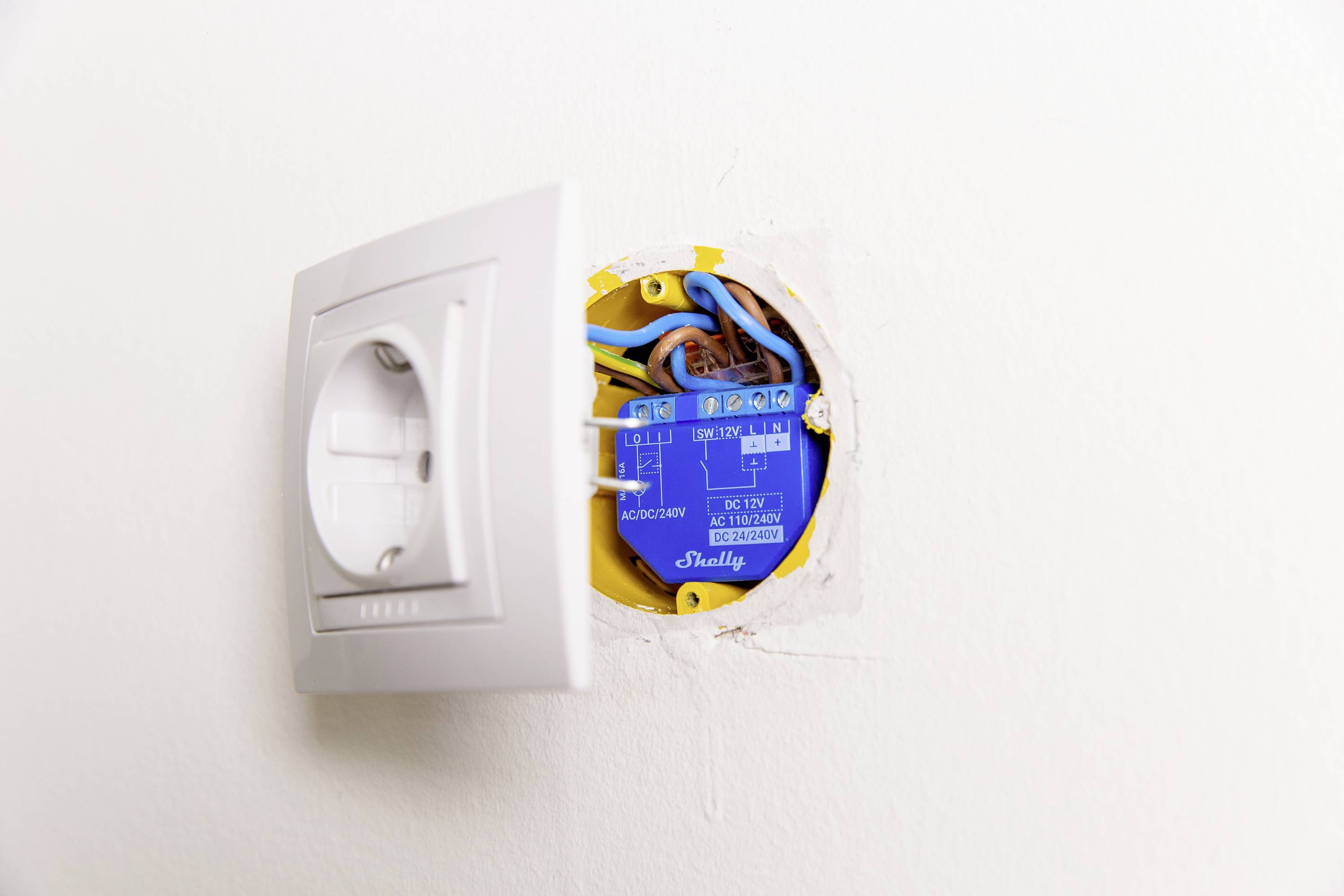 Lichtschalter mit sichtbarer Verkabelung in einer Wandöffnung. Schalterabdeckung ist teilweise entfernt, elektrische Drähte sind zu sehen.