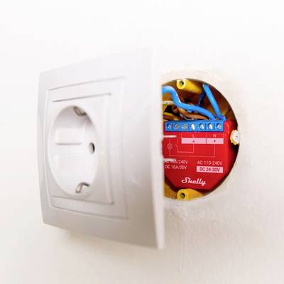 Eine geöffnete Steckdose mit sichtbarer, verkabelter Elektronikbauteil im Inneren.