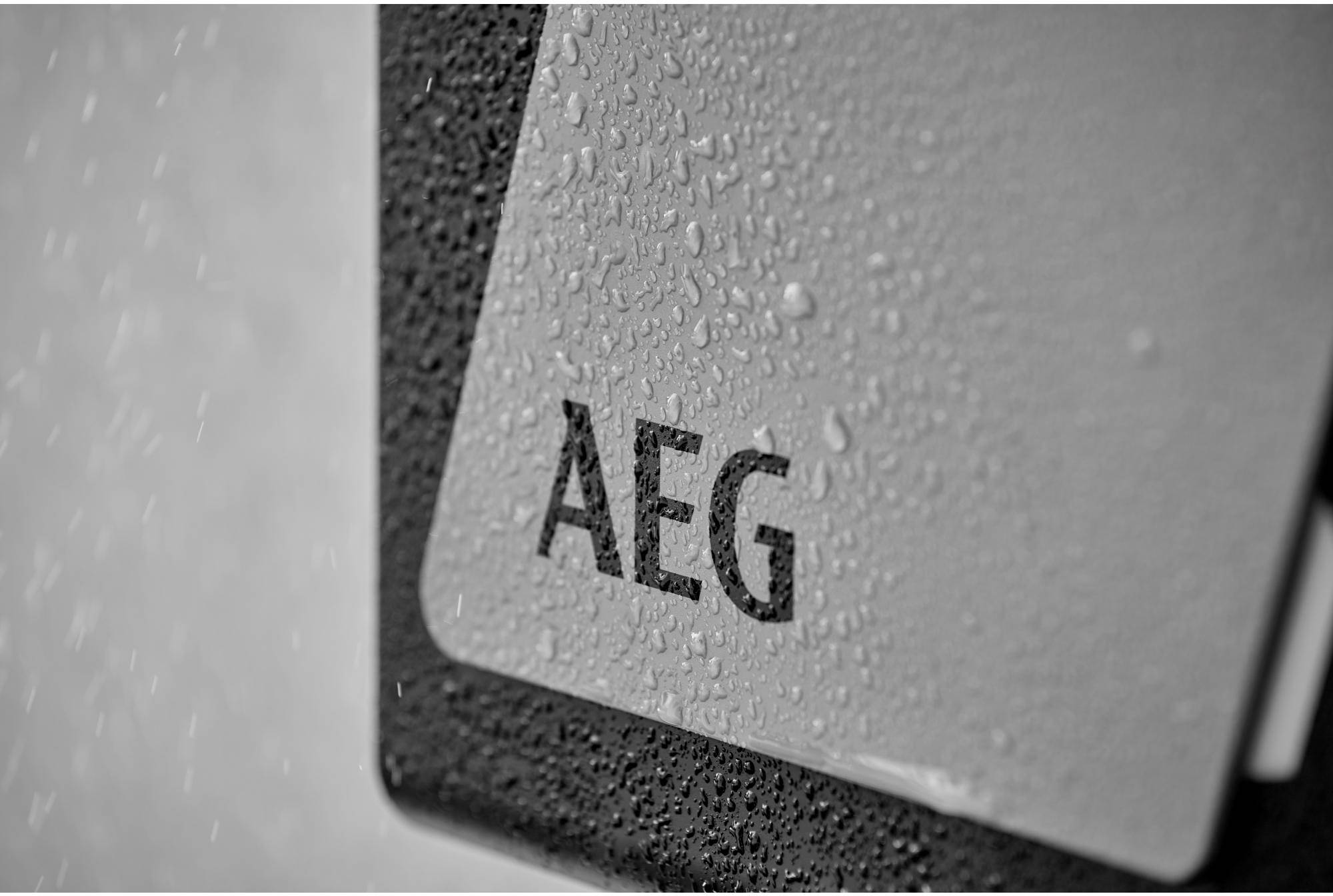 Nasses Gerät mit dem Logo 'AEG', bedeckt von Wassertropfen.