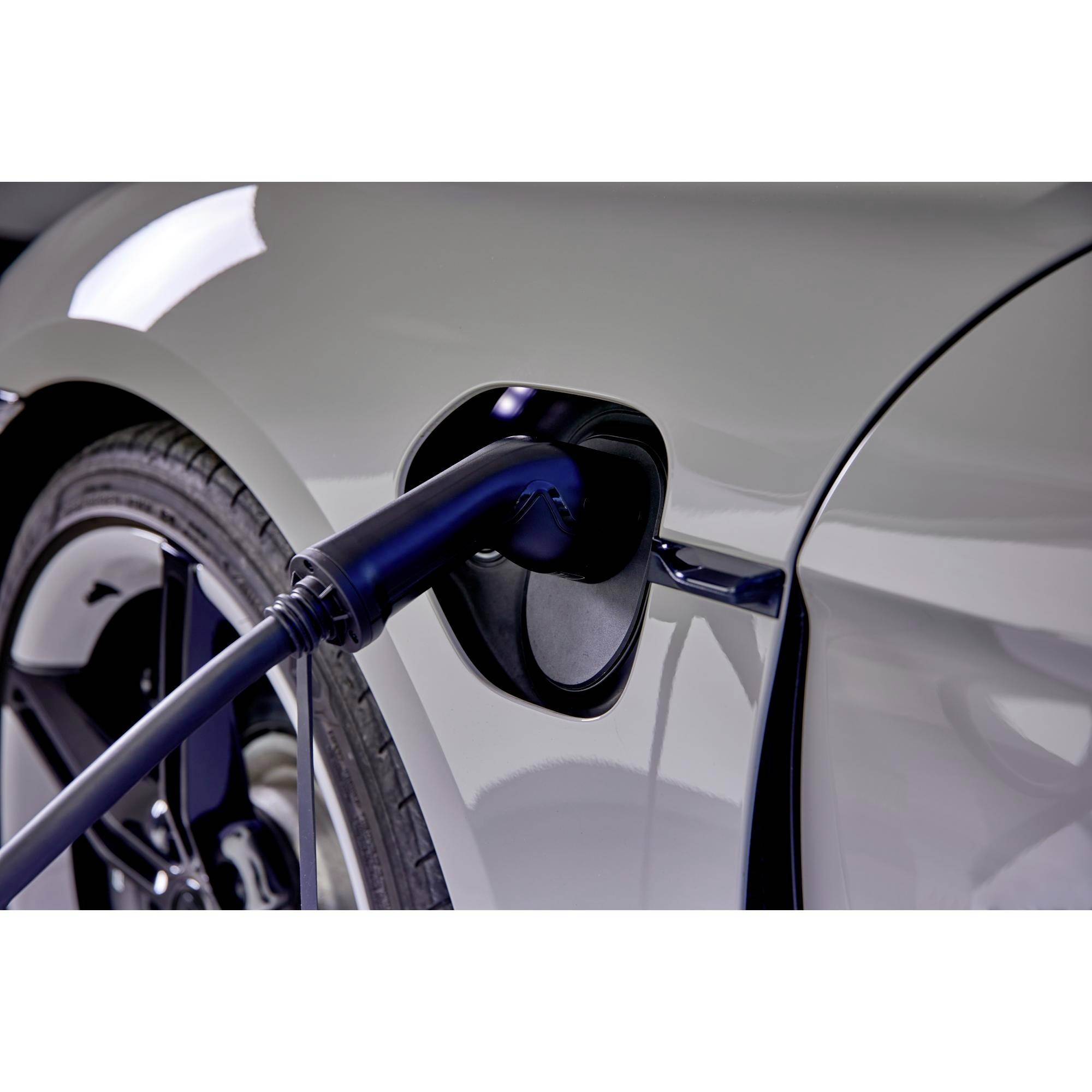 Ein Elektroauto wird an einer Ladestation geladen, der Ladestecker ist angeschlossen. Das Auto ist grau und befindet sich im Ladeprozess.