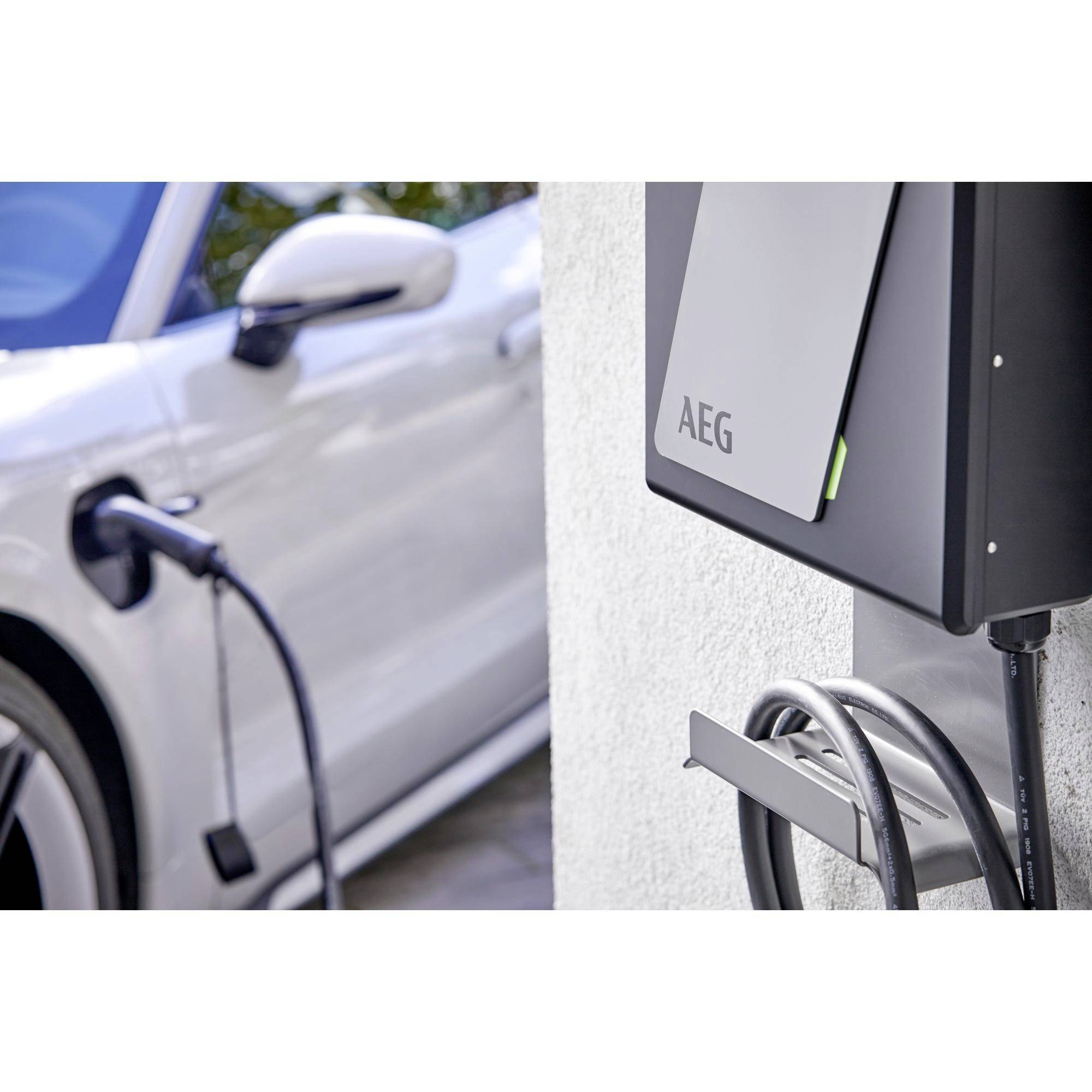 Ein weißes Auto wird an einer Wandladestation von AEG aufgeladen. Ein Ladekabel verbindet das Auto mit der Station.