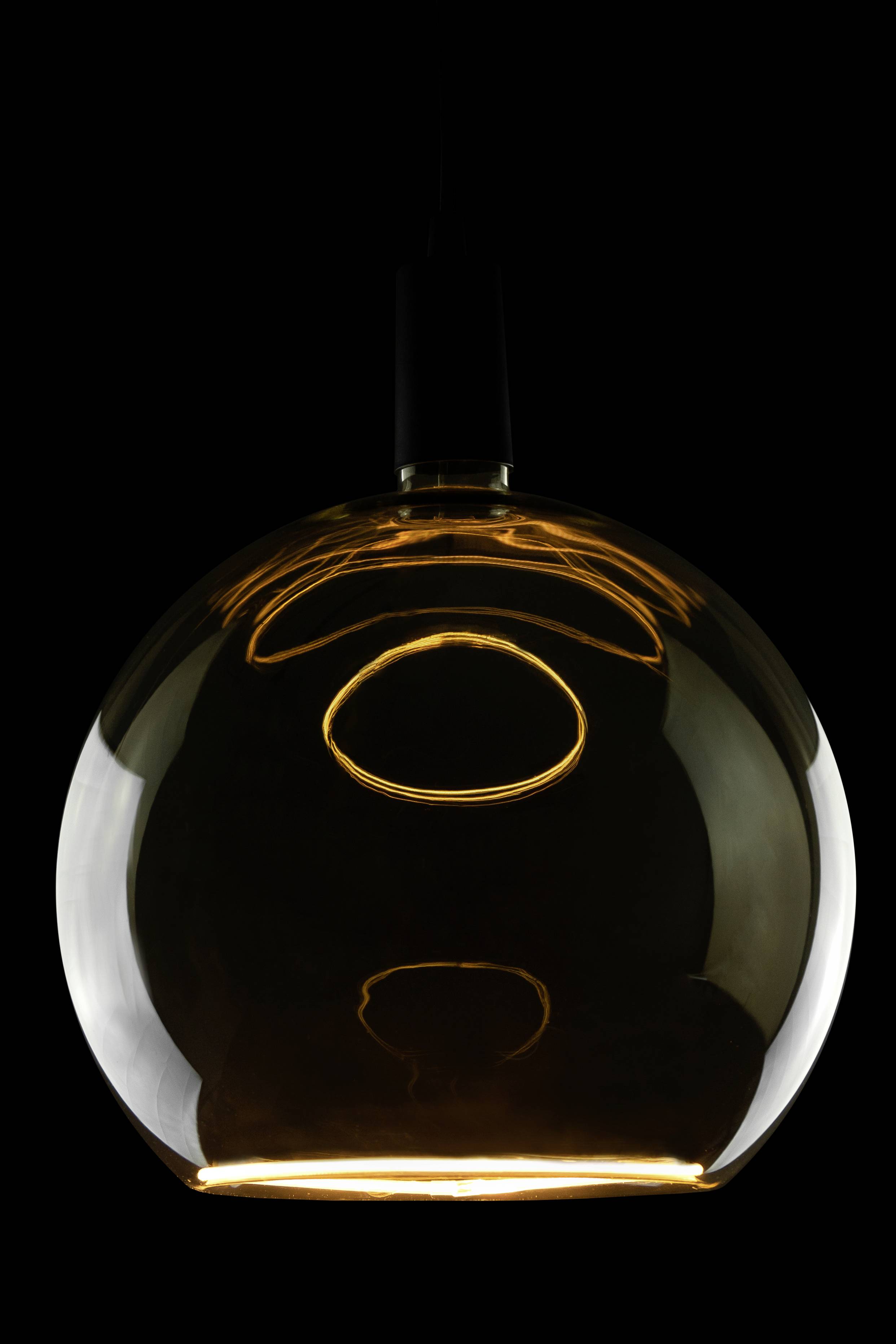 Eine kugelförmige, beleuchtete Lampe aus Glas, die von oben hängt, vor einem dunklen Hintergrund. Sie erzeugt warmes Licht.