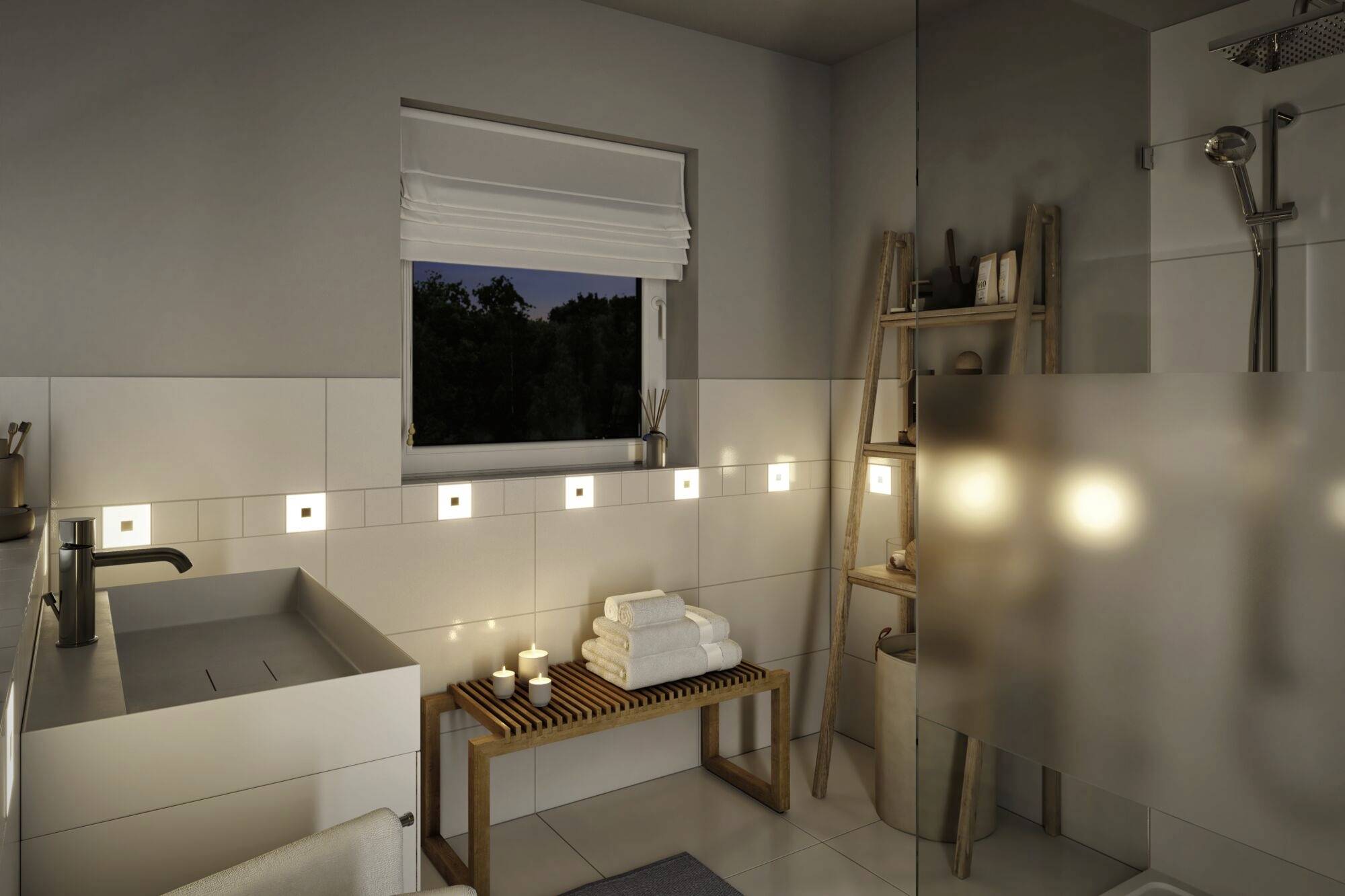 Modernes Badezimmer mit Waschbecken, Holzbank und Kerzen. Dunkles Fenster zeigt Abendlage. Deko-Leiter mit Handtüchern und Regendusche.