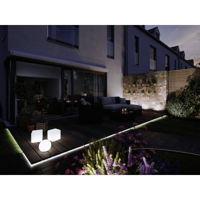 Moderne Terrasse bei Dämmerung mit Beleuchtung, Möbeln und einer mit Pflanzen verzierten Wand im Hintergrund.