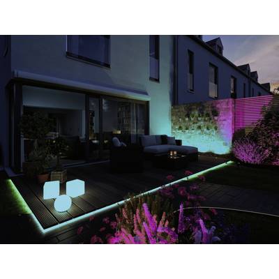 Ein Garten bei Dämmerung mit bunten LED-Lichtern: leuchtende Kuben auf dem Boden, in den Pflanzen und entlang der Terrassenkante.