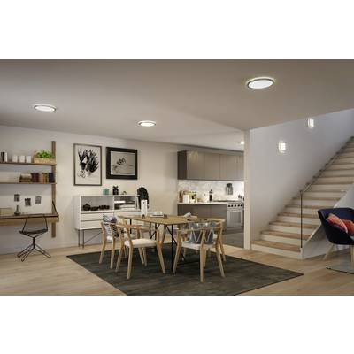 Ein modernes Esszimmer mit Tisch und Stühlen, einer Treppe rechts und einer Küche im Hintergrund. Dezente Beleuchtung und Wanddekoration.