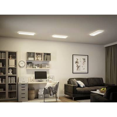 Ein stilvolles Wohnzimmer mit Schreibtischecke: graues Sofa, Computer auf weißem Tisch, beige Bücherregale, gedämpfte Beleuchtung.