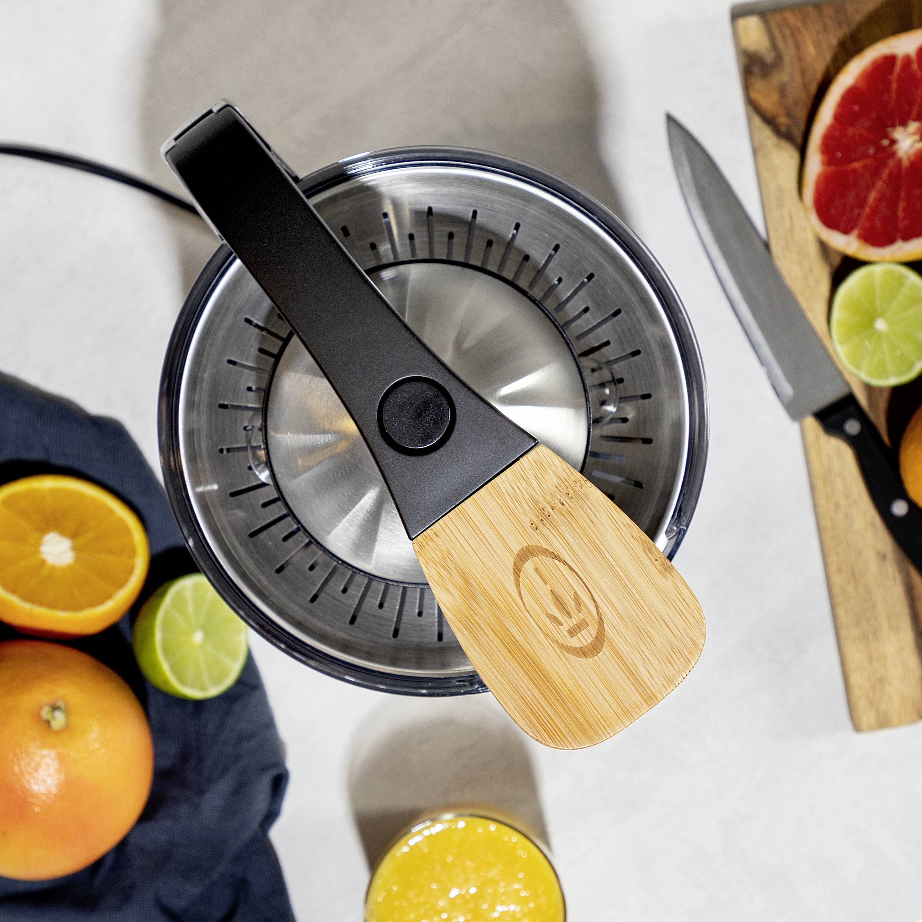 Frisch gepresster Saft mit Zitrusfrüchtepresse, umgeben von geschnittenen Orangen, Limetten und Grapefruit.