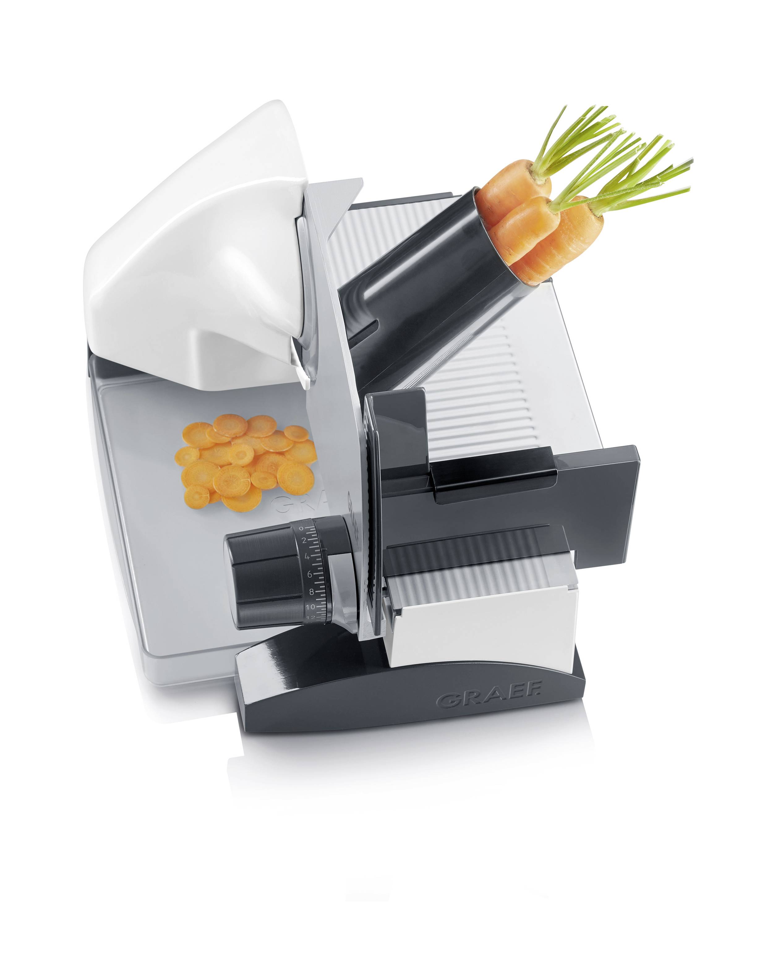 Elektrische Allesschneider-Maschine schneidet Karotten in Scheiben. Obere Karotten im Halter, geschnittene Scheiben auf der Platte.