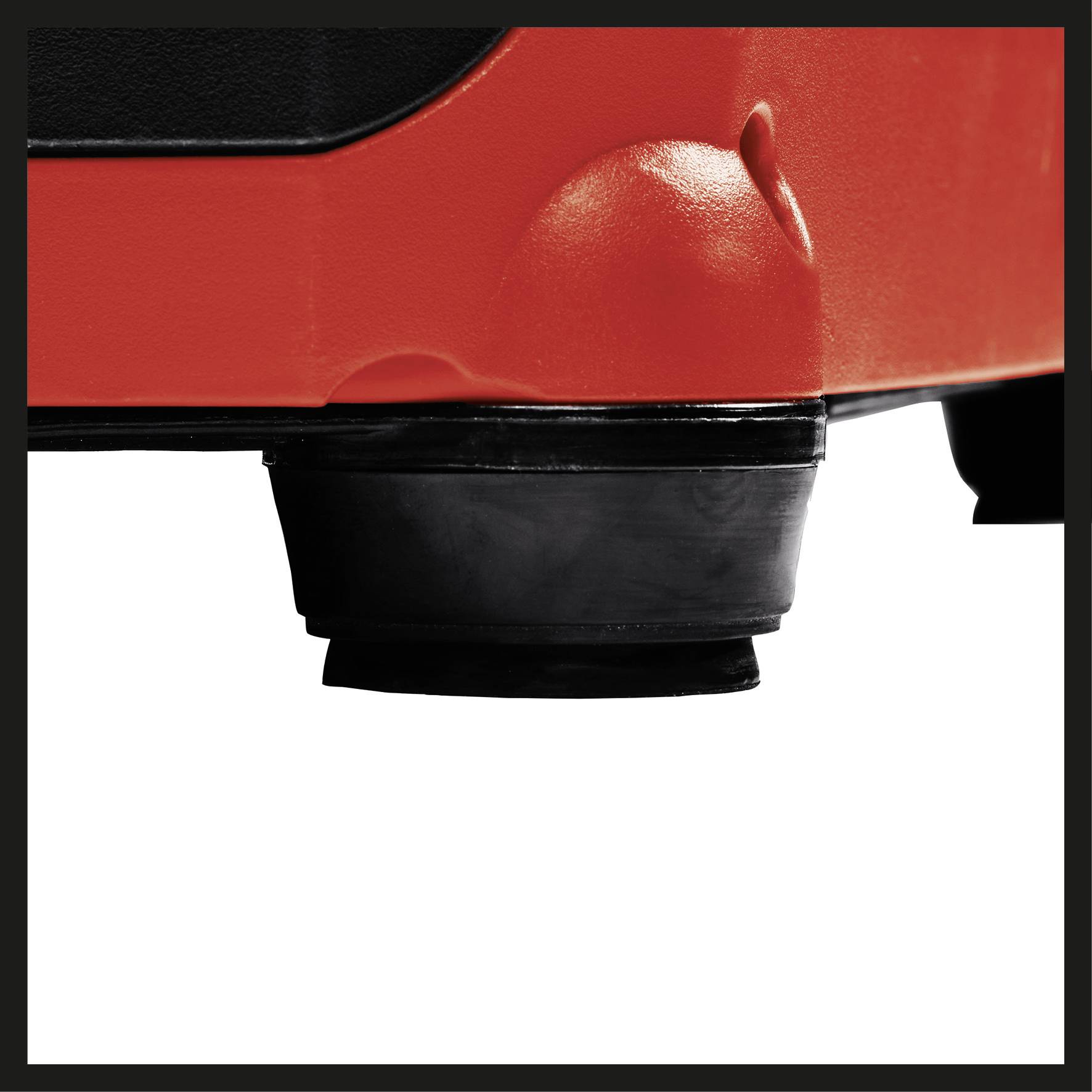 Eine schwarze runde Gummifüße stützt ein rotes Geräteunterteil auf einer ebenen Fläche ab.