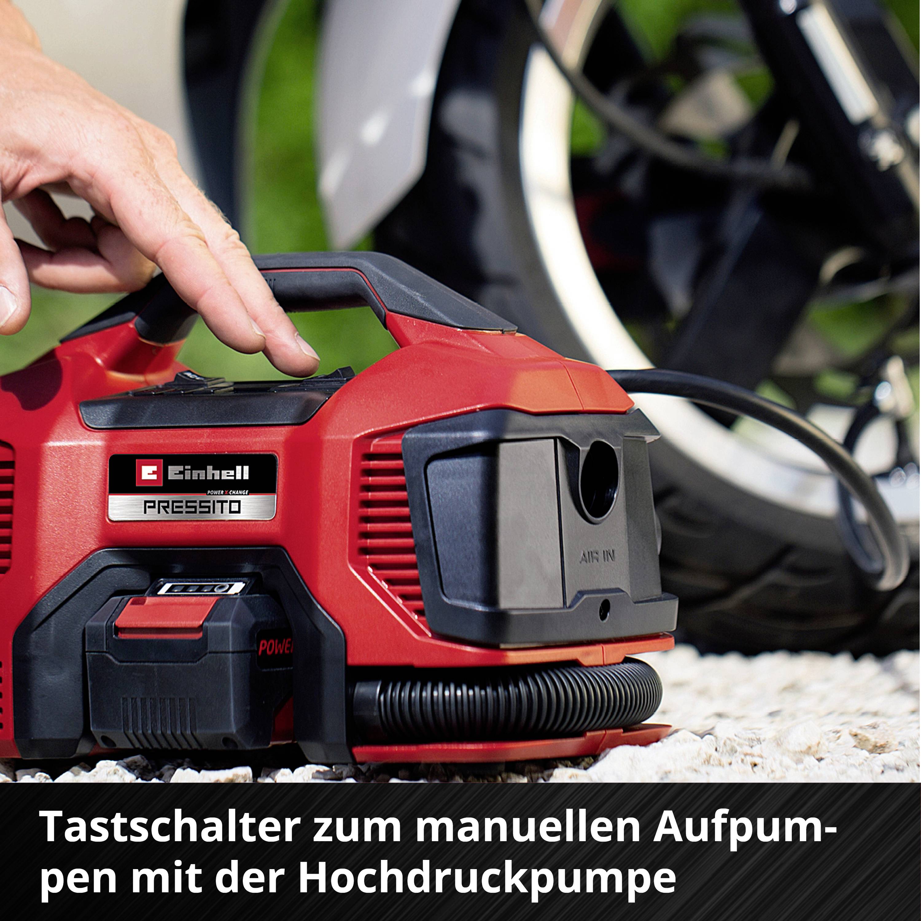Person bedient roten Kompressor mit einem schwarzen Hebel. Text: 'Tastschalter zum manuellen Aufpumpen mit der Hochdruckpumpe'.