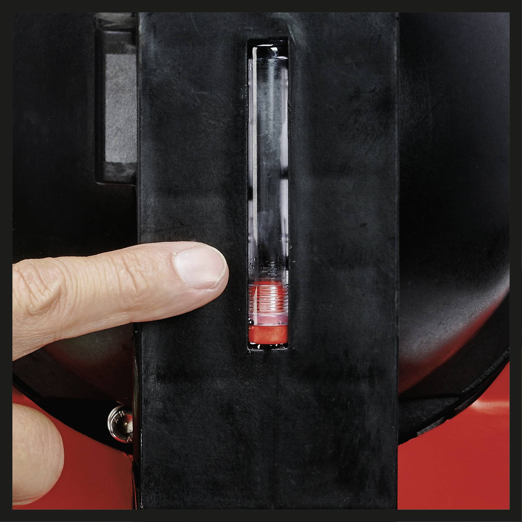 Finger zeigt auf einen transparenten Zylinder mit rotem Balken in einem schwarzen Gehäuse.