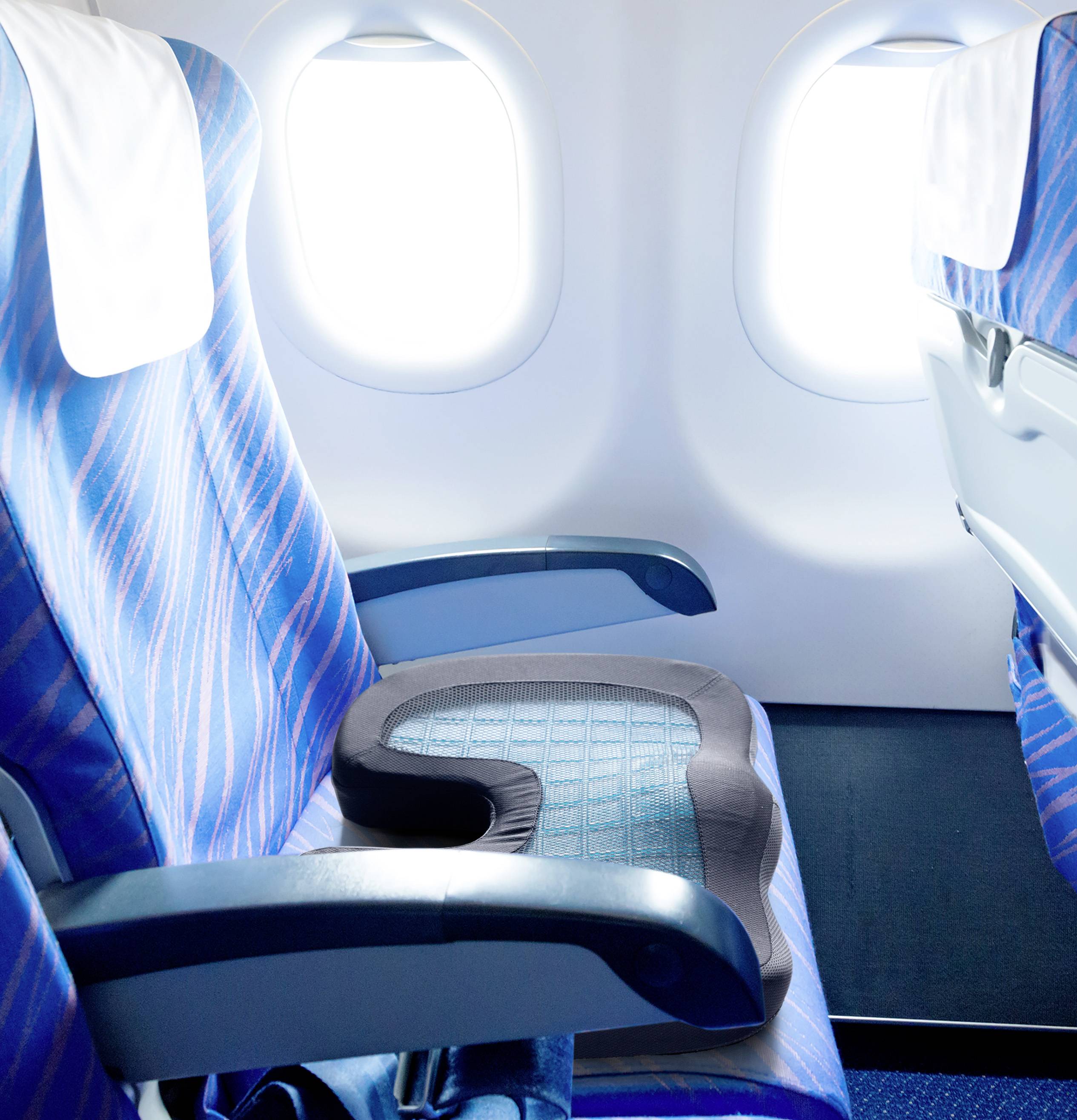 Blick auf leere Flugzeugsitze mit blauen Bezügen und einem Fenster im Hintergrund.