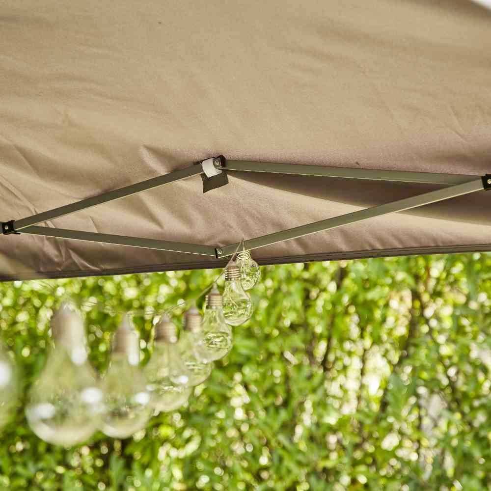 Dekoration mit hängenden Glühbirnen unter einem Zeltdach vor grünem Hintergrund. Entspannte, sommerliche Atmosphäre.