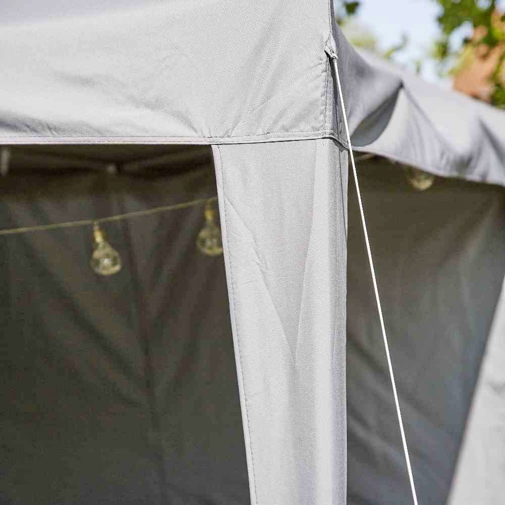 Ein graues Zelt mit Lichterketten darunter hängt in einem Außenbereich.