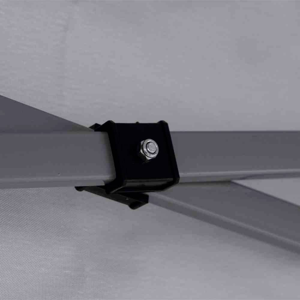 Nahaufnahme einer Metallverbindung mit Schraube an einem Rahmen, möglicherweise Teil eines Zelts oder Konstrukts, in einem Innenraum.