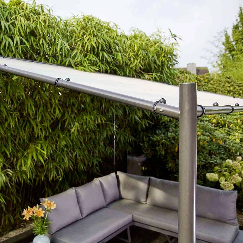 Ecksofa im Garten mit Überdachung, umgeben von Pflanzen und einem kleinen Tisch mit Vase, bietet einen gemütlichen Sitzbereich.