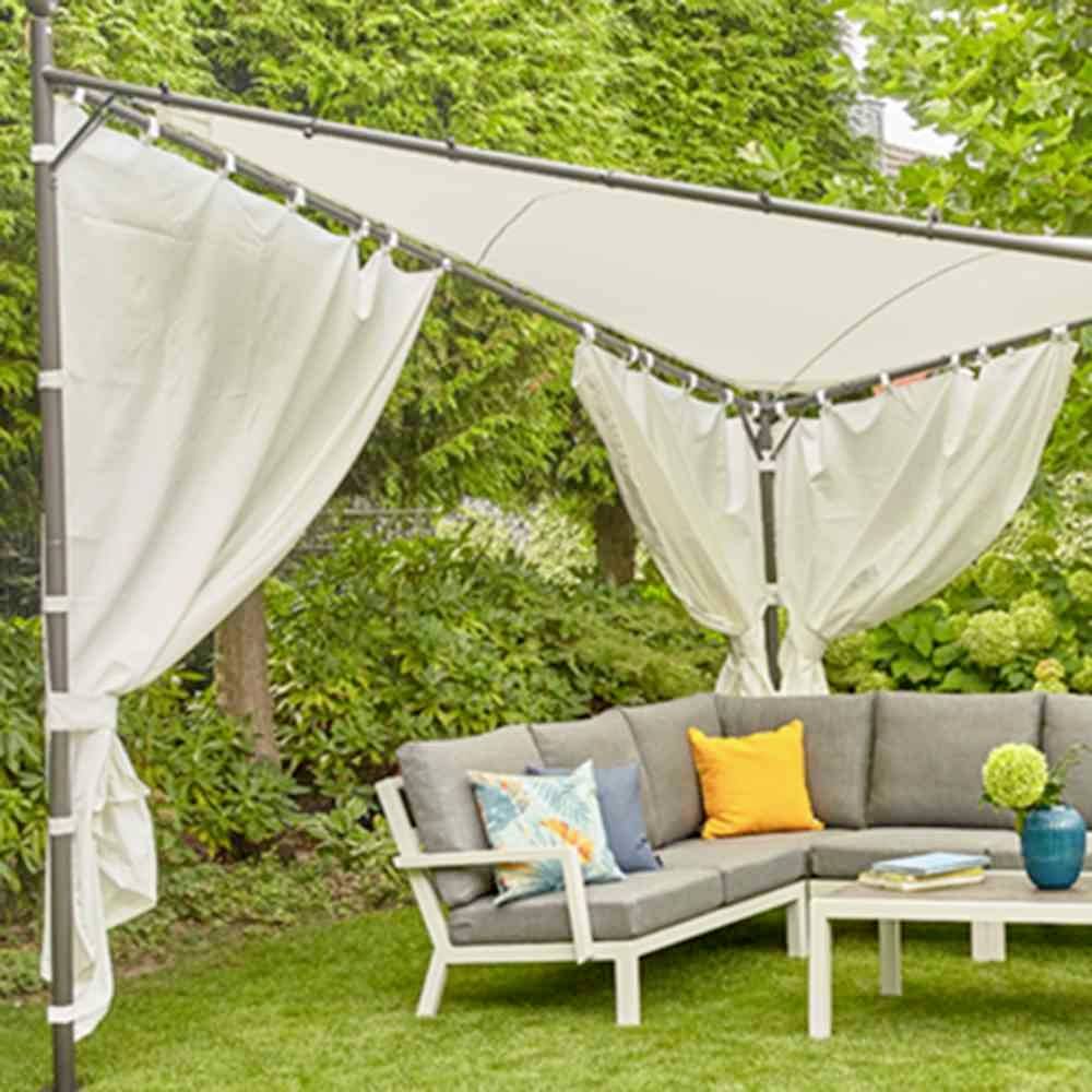 Ein Gartensofa mit bunten Kissen steht unter einem Sonnensegel. Umgeben von Pflanzen, wirkt die Szene einladend und entspannend.