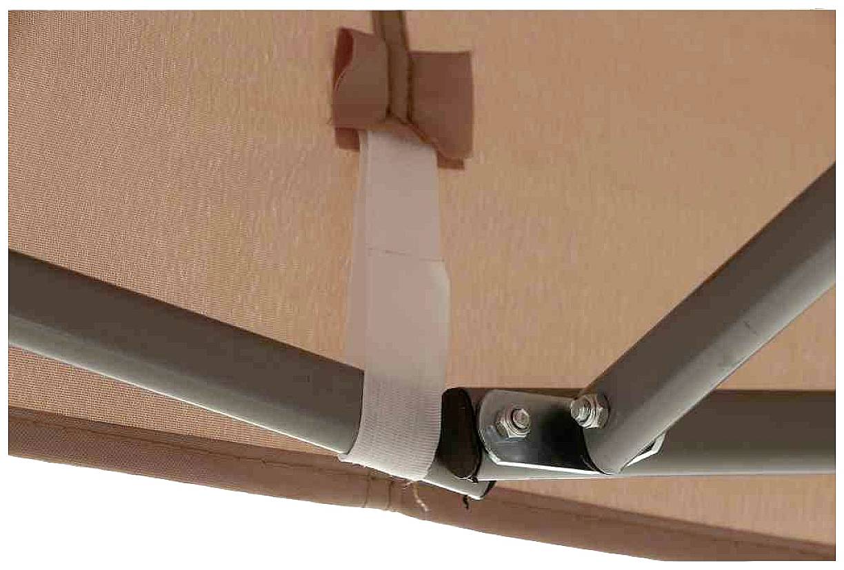 Nahaufnahme einer Metallstruktur, die mit einem cremefarbenen Stoffband verbunden ist. Oberhalb ist ein beigefarbener Stoff zu sehen.