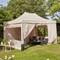 Ein beiger Pavillon in einem sonnigen Garten mit Sitzecke, umgeben von Pflanzen und Bäumen. Ideal für Entspannung im Freien.
