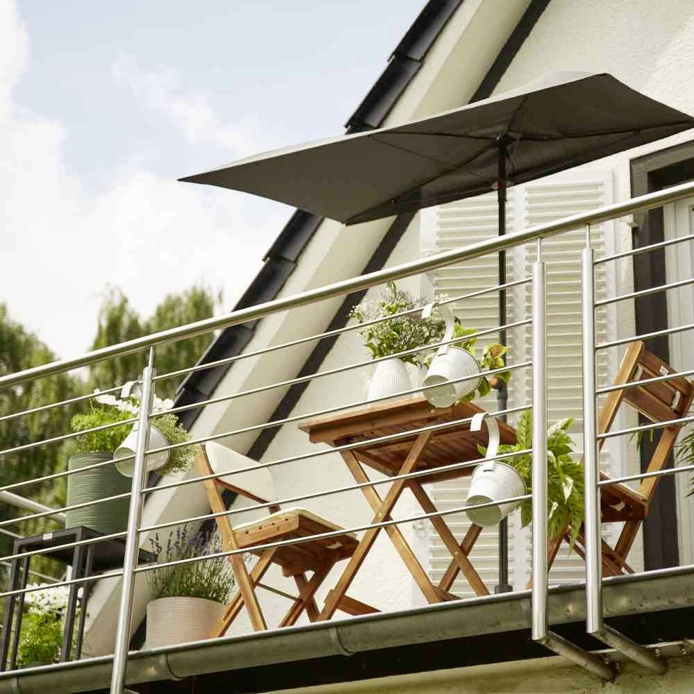 Ein Balkon mit Holzmöbeln, Tisch und Stühlen, dekoriert mit Pflanzen. Ein Sonnenschirm bietet Schutz vor der Sonne.