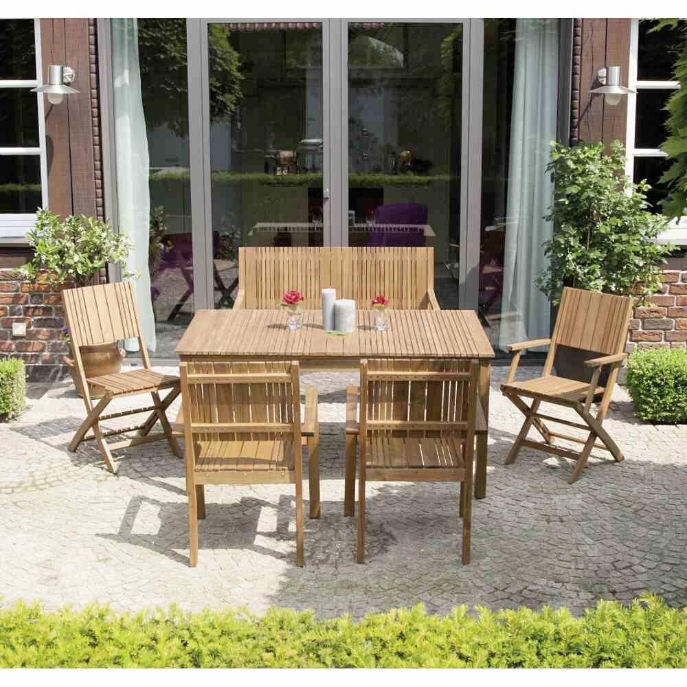 Holz-Essgruppe im Freien auf einer Terrasse vor großen Fenstern. Tisch mit vier Stühlen, zwei Kerzen und zwei Rosen darauf.