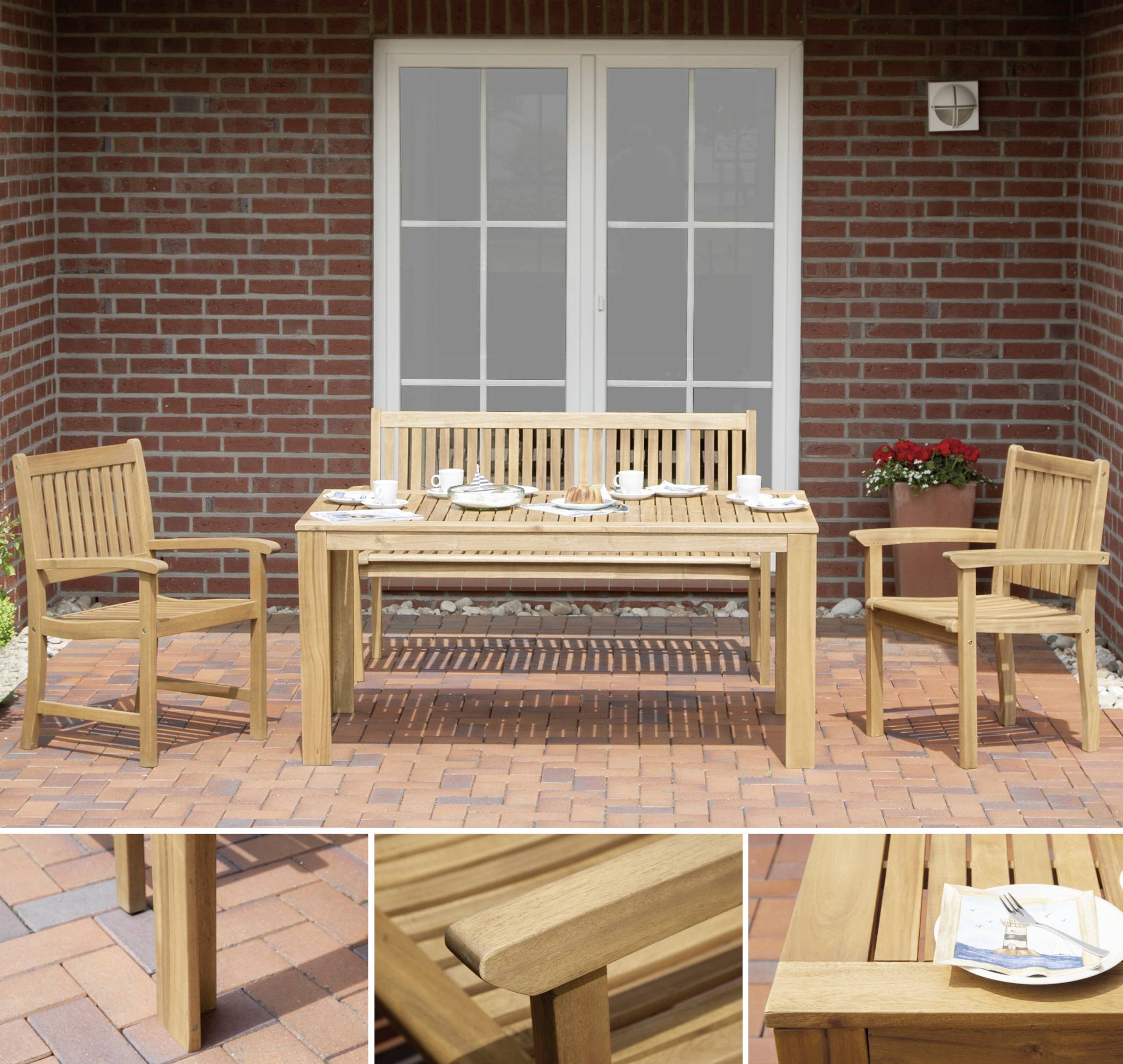 Holzterrassentisch mit Stühlen auf rotem Backsteinboden, gedeckt mit Geschirr für vier Personen. Ziegelwand im Hintergrund.