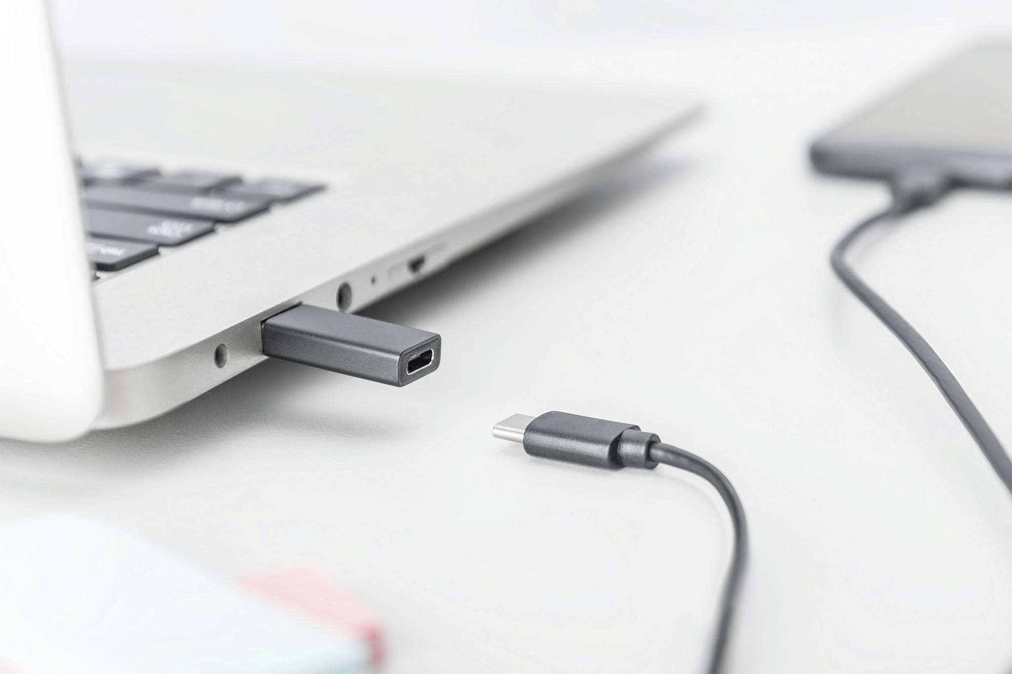 Computer mit eingestecktem USB-Stick und daneben ein USB-Kabel auf einem Tisch.