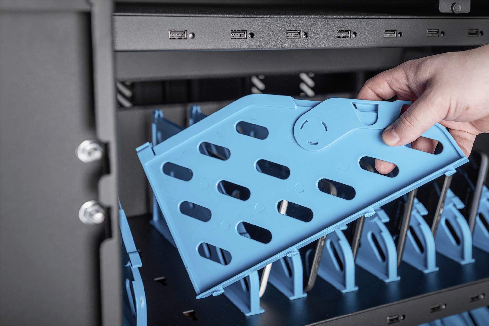 Eine Hand fügt ein blaues Gitter in ein Serverrack ein, um Kabel zu organisieren. Im Hintergrund sind Netzwerkanschlüsse zu sehen.