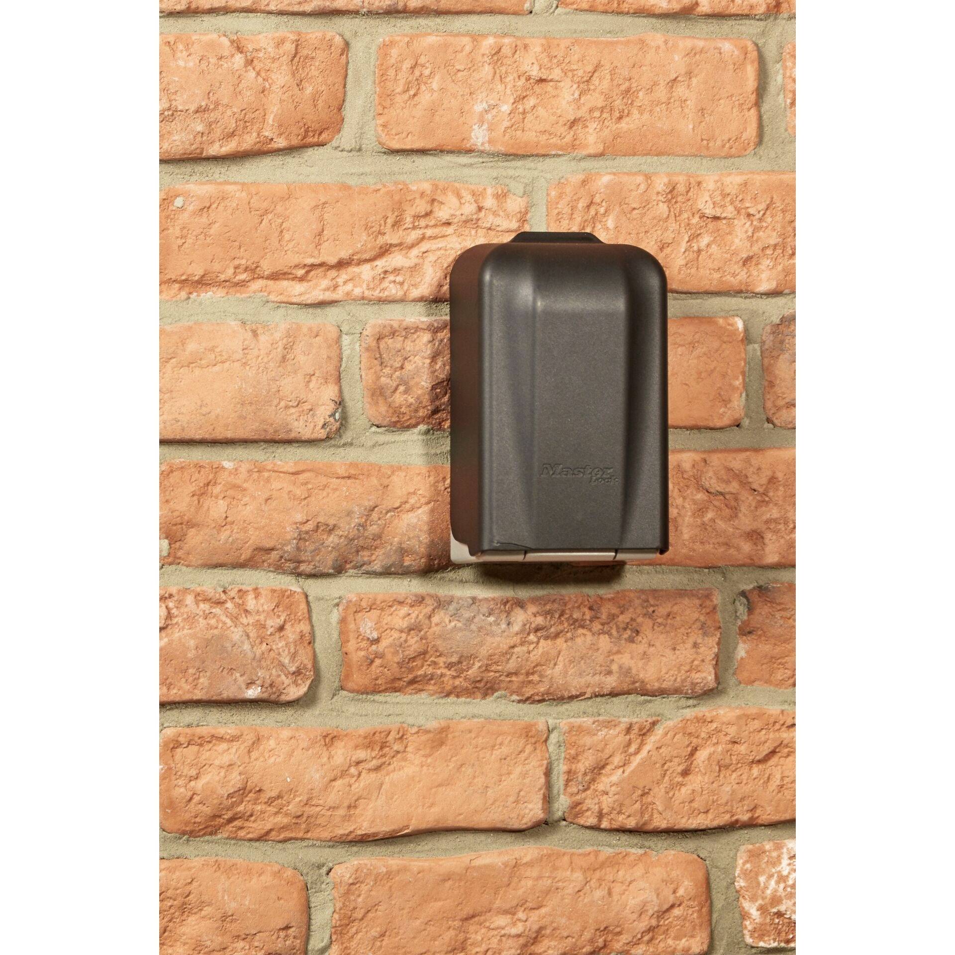 Ein schwarzes Gehäuse ist an einer roten Backsteinwand montiert.