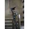 Ein schwarzer E-Scooter ist an einem Metallzaun mit einem Schloss gesichert. Der Hintergrund ist unscharf.