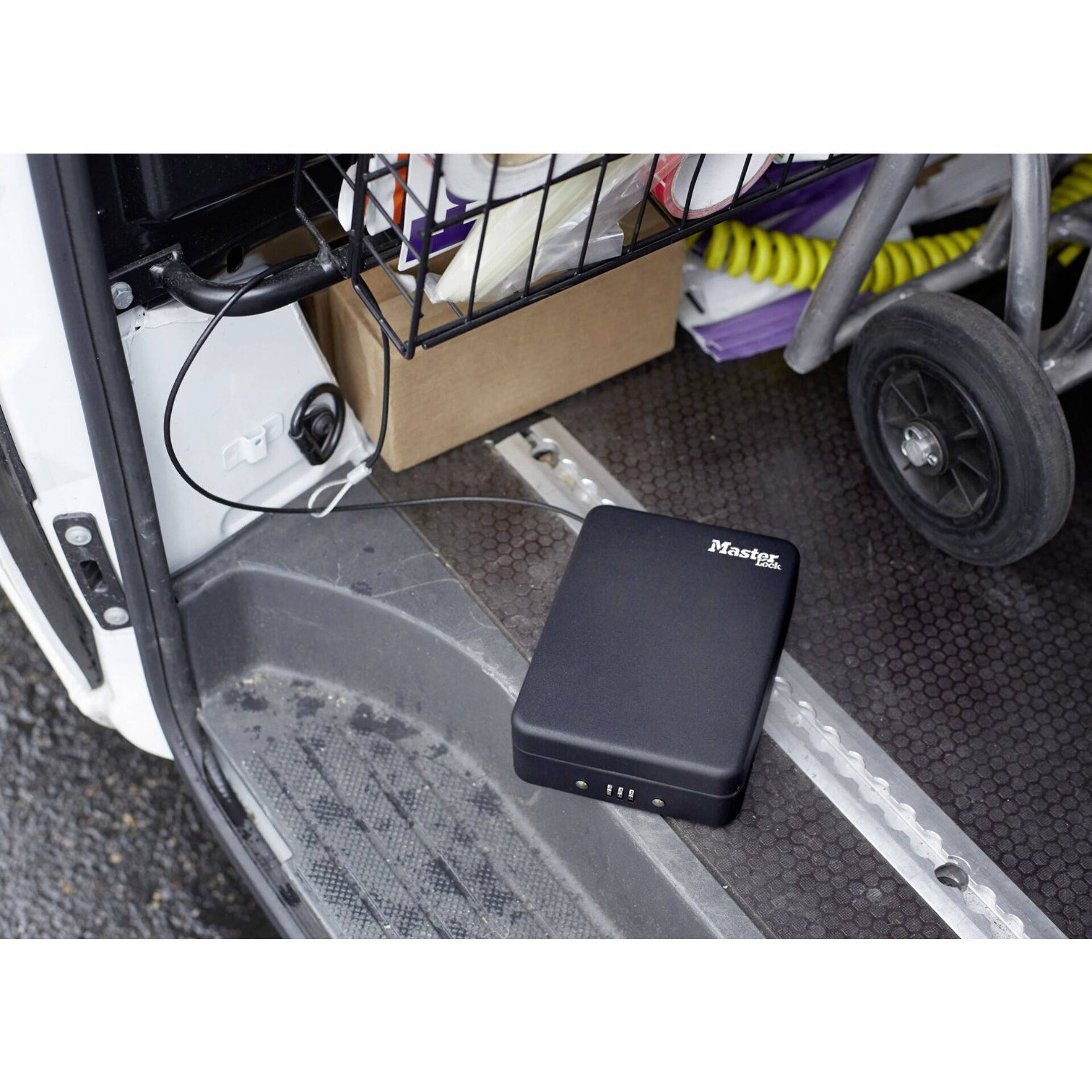 Eine tragbare Batteriebox mit dem Logo 'Master' auf einem Fahrzeugboden, verbunden mit einem Gerät im Auto.