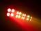 Ein lebhaftes Lichtmuster mit abwechselnden roten, grünen und weißen Scheinwerfern, die in Reihen angeordnet sind und in den Raum strahlen.