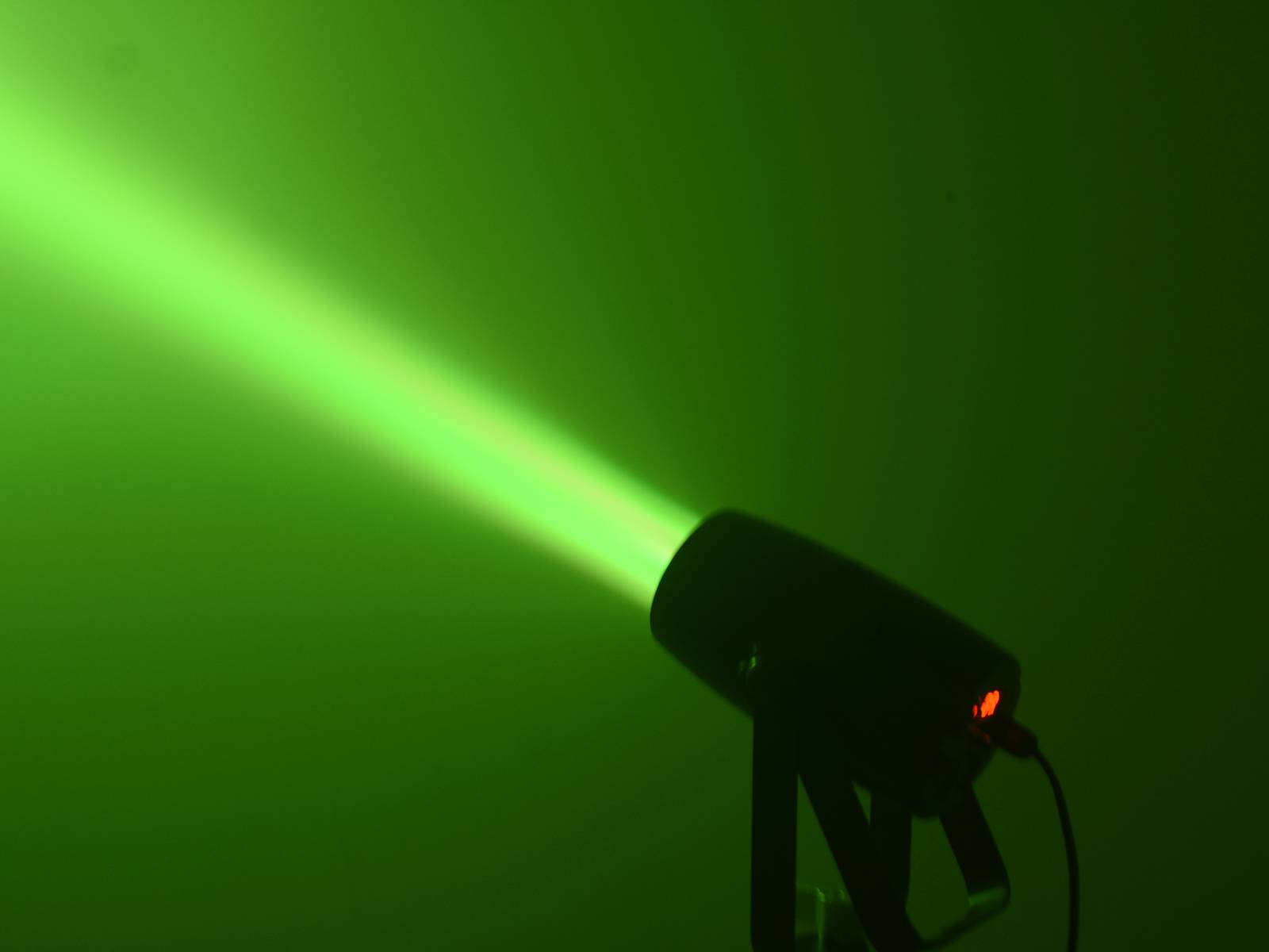 Grüne Laserlicht-Projektion strahlt von einem Gerät aus, das auf einem Stativ montiert ist; erzeugt einen hellen Lichtstrahl.