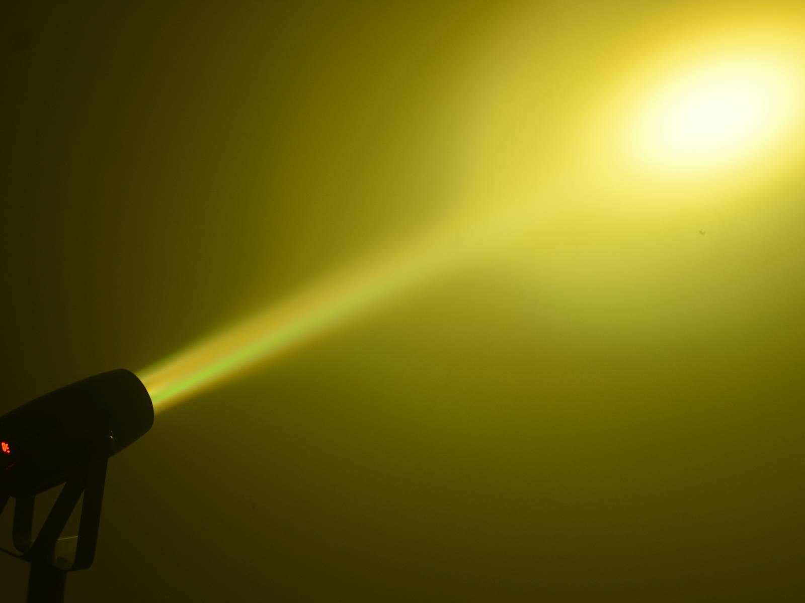 Lichtstrahl aus Scheinwerfer, der gelblich leuchtet, auf dunklem Hintergrund.