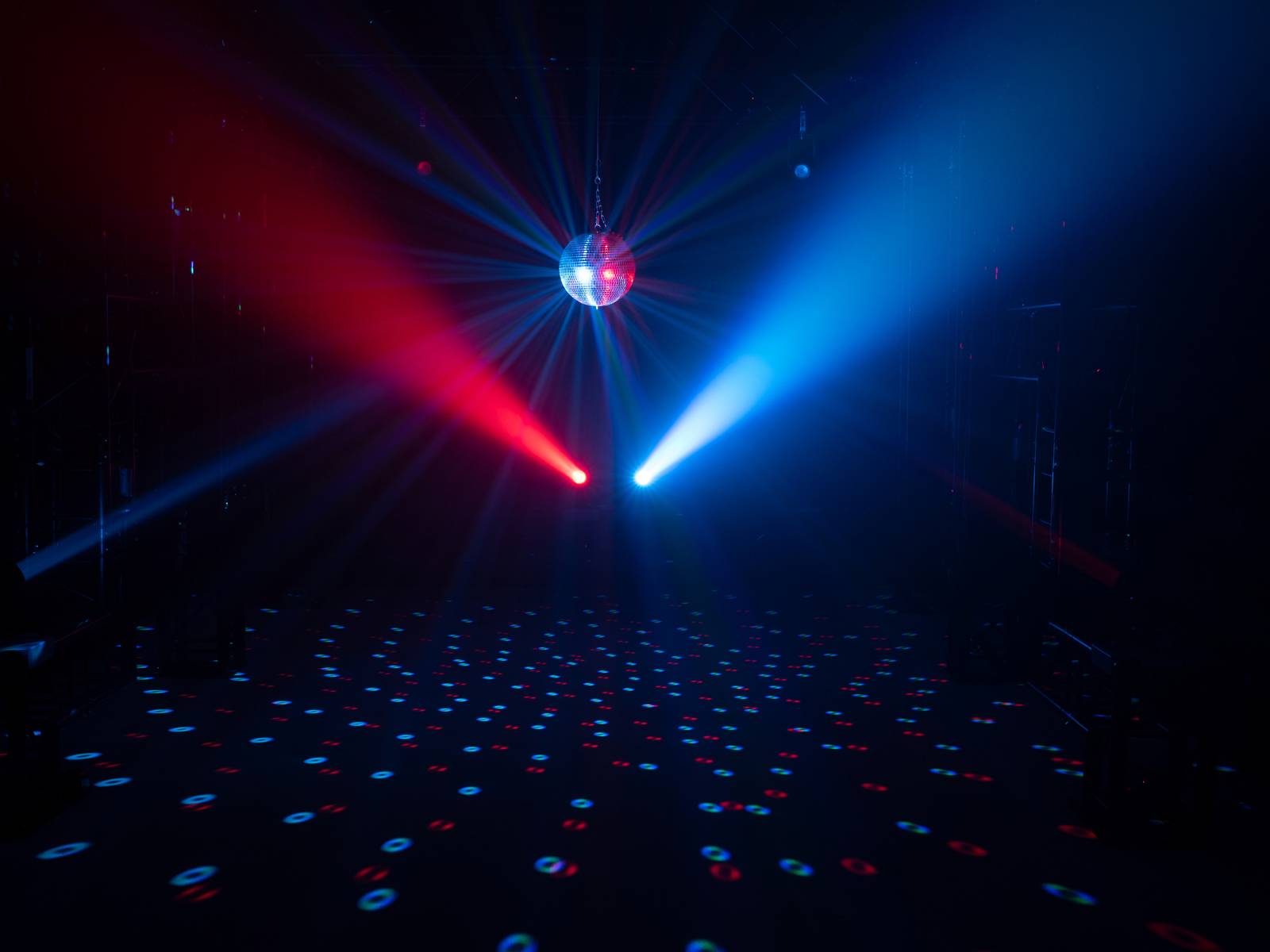Tanzfläche mit Discokugel, rotem und blauem Lichtstrahl, schafft eine partyähnliche Atmosphäre.