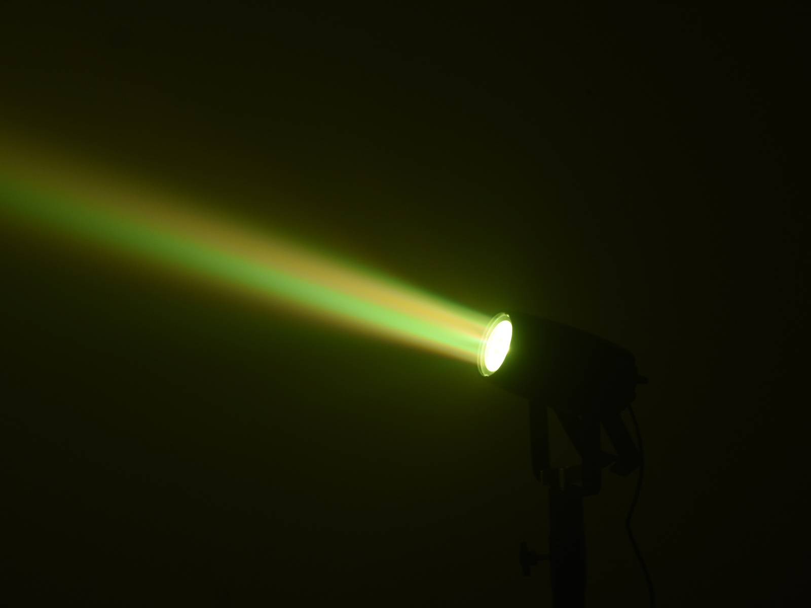 Ein Scheinwerfer projiziert einen schmalen, grünen Lichtstrahl in einem dunklen Raum.