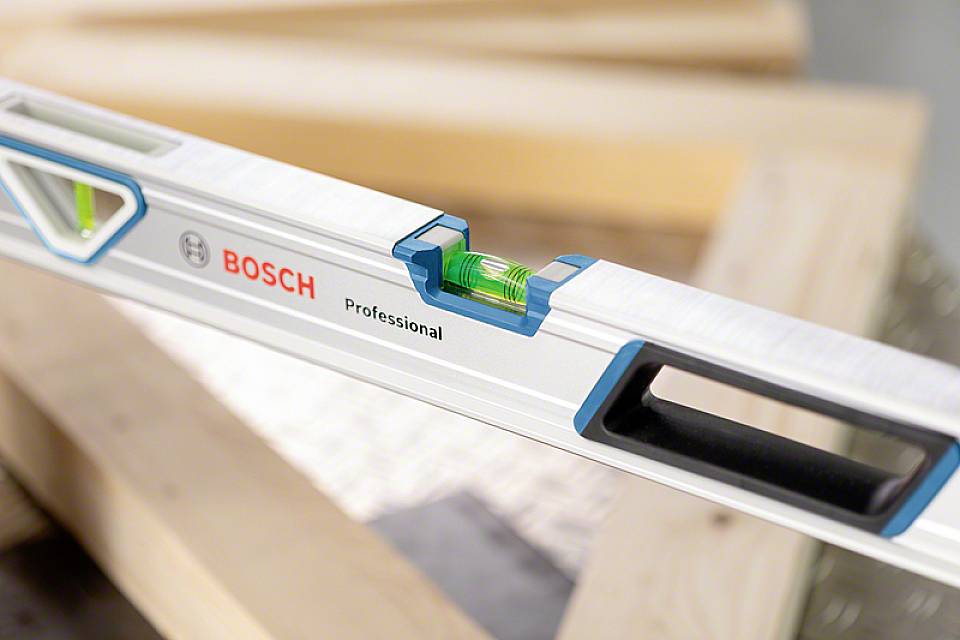 Wasserwaage mit grüner Libelle zur Nivellierung; Aufschrift 'BOSCH Professional'. Liegt auf Holzbalken.