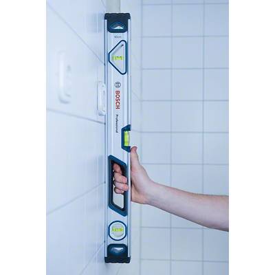 'Eine Hand hält eine Wasserwaage senkrecht an einer gefliesten Wand. Die Wasserwaage zeigt an, ob die Wand perfekt ausgerichtet ist.'