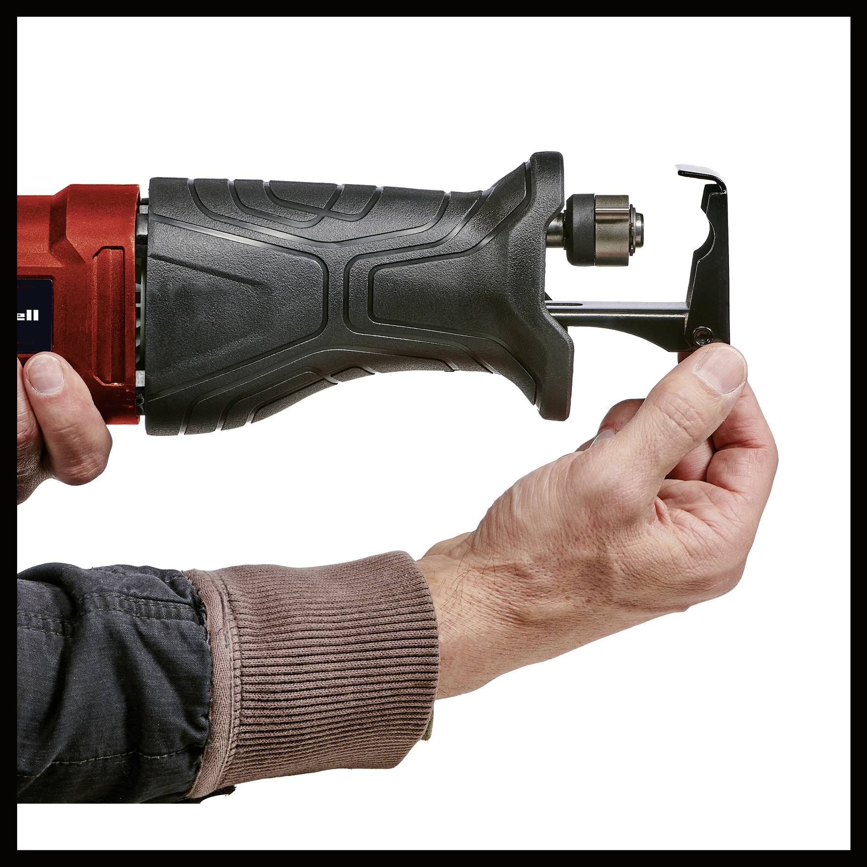 Eine Person hält eine rote elektrische Säge und zeigt, wie man ein Sägeblatt wechselt, indem sie eine Abdeckung öffnet.