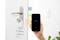 Ein Smartphone steuert ein Smart-Lock an einer Tür. Es ist kompatibel mit 'Hey Google', 'Apple HomeKit' und 'Amazon Alexa'.