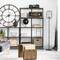 Wohnzimmer mit grauem Sofa, großen Wanduhr, schwarzen Regalen mit Büchern und Dekorationen, und Holzbeistelltischen. Elegantes, modernes Design.