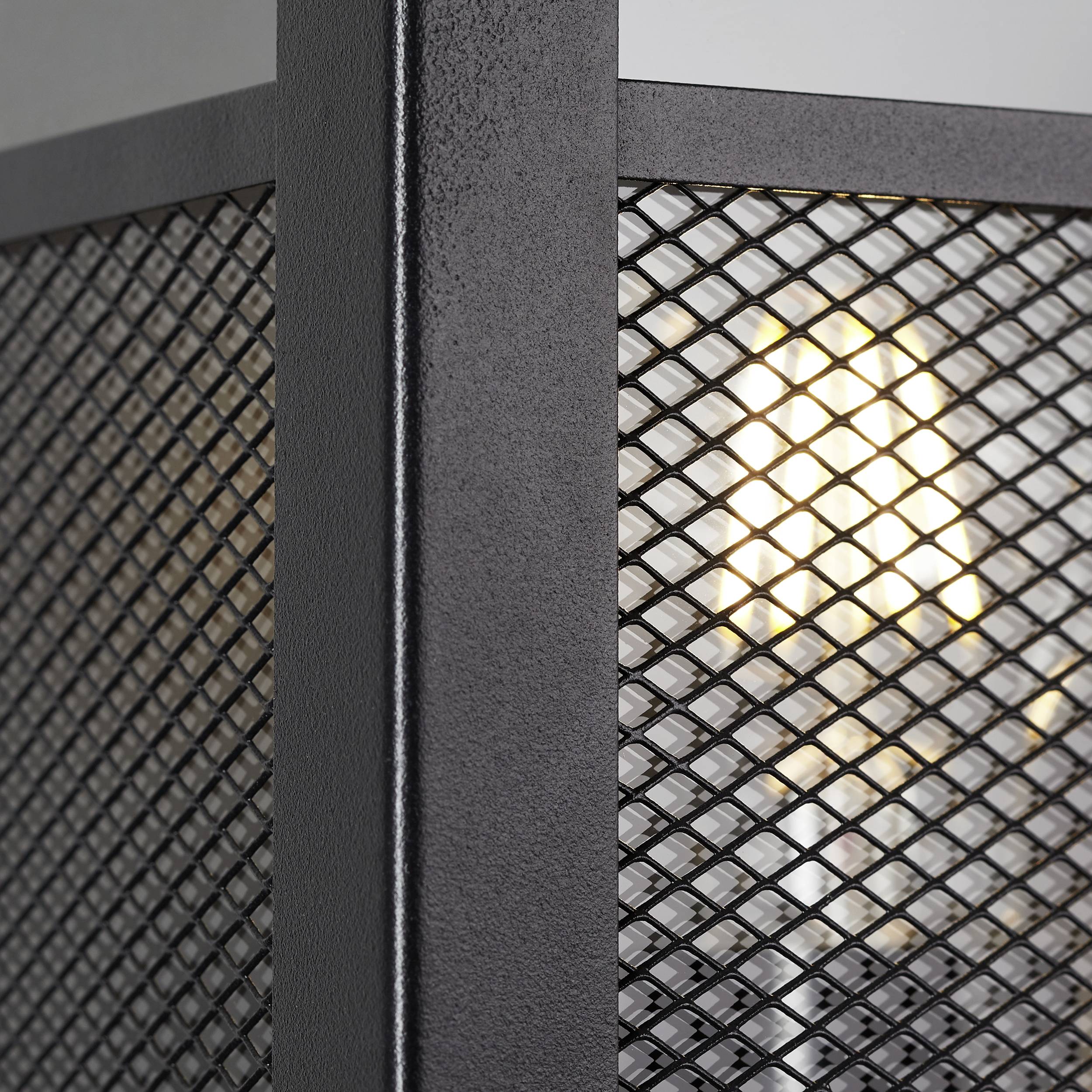 Eine leuchtende Glühbirne hinter einem Metallgitter in einem industriellen Design.