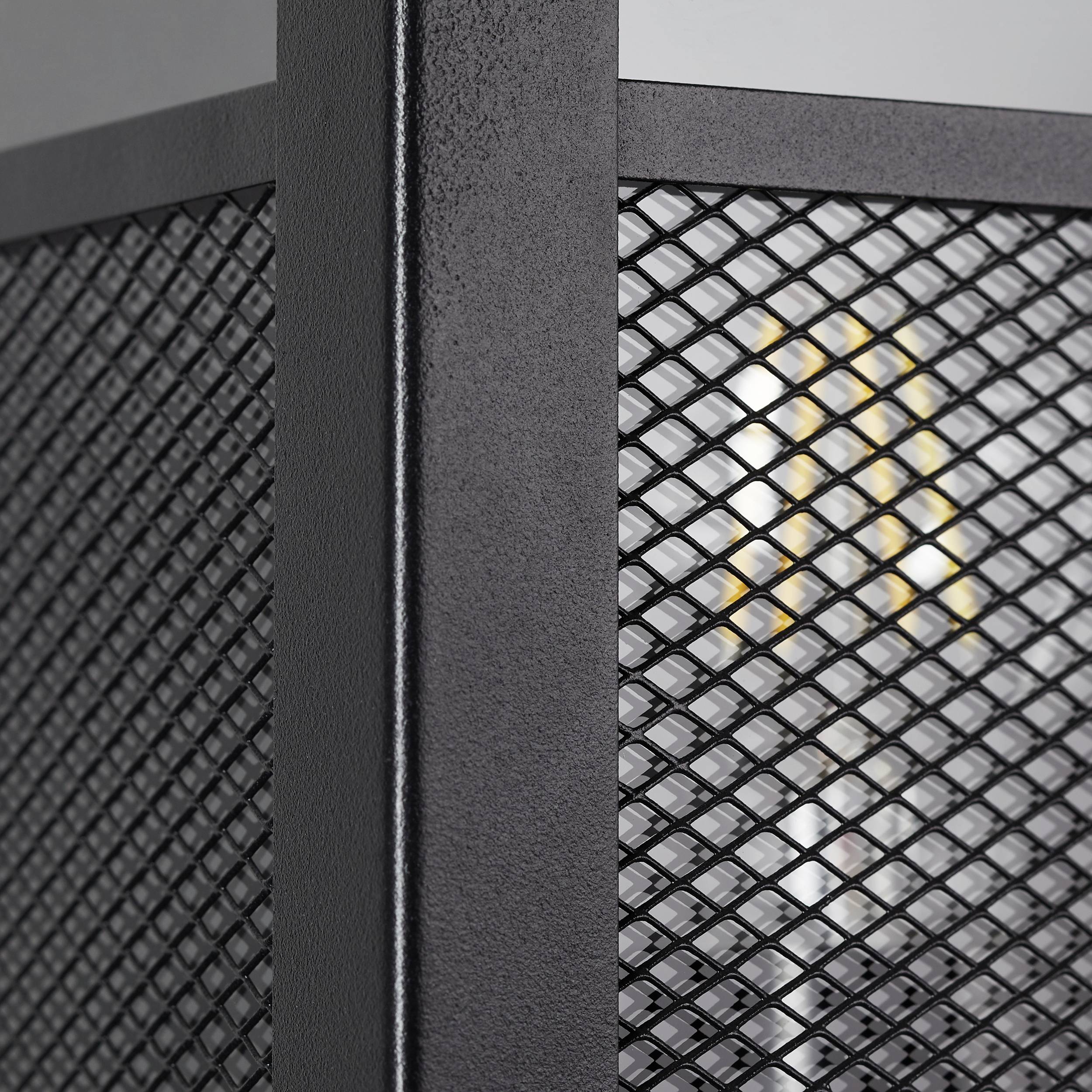 Schwarzes, industrielles Metallgitter mit sichtbaren Glühbirnen hinter der Struktur; Detail einer modernen Inneneinrichtung.