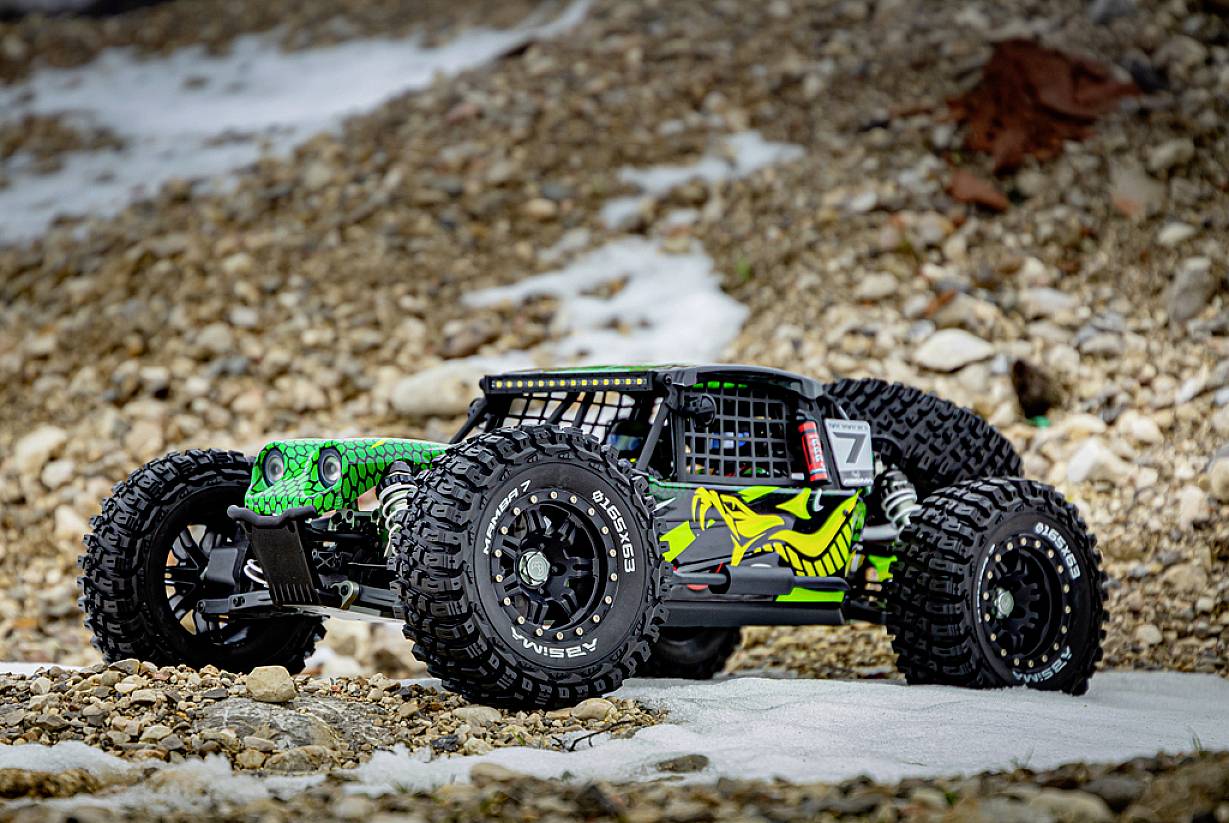 Ein ferngesteuertes Auto im Offroad-Design fährt über eine steinige Fläche. Das Auto hat große Reifen und ein auffälliges, grünes Design.