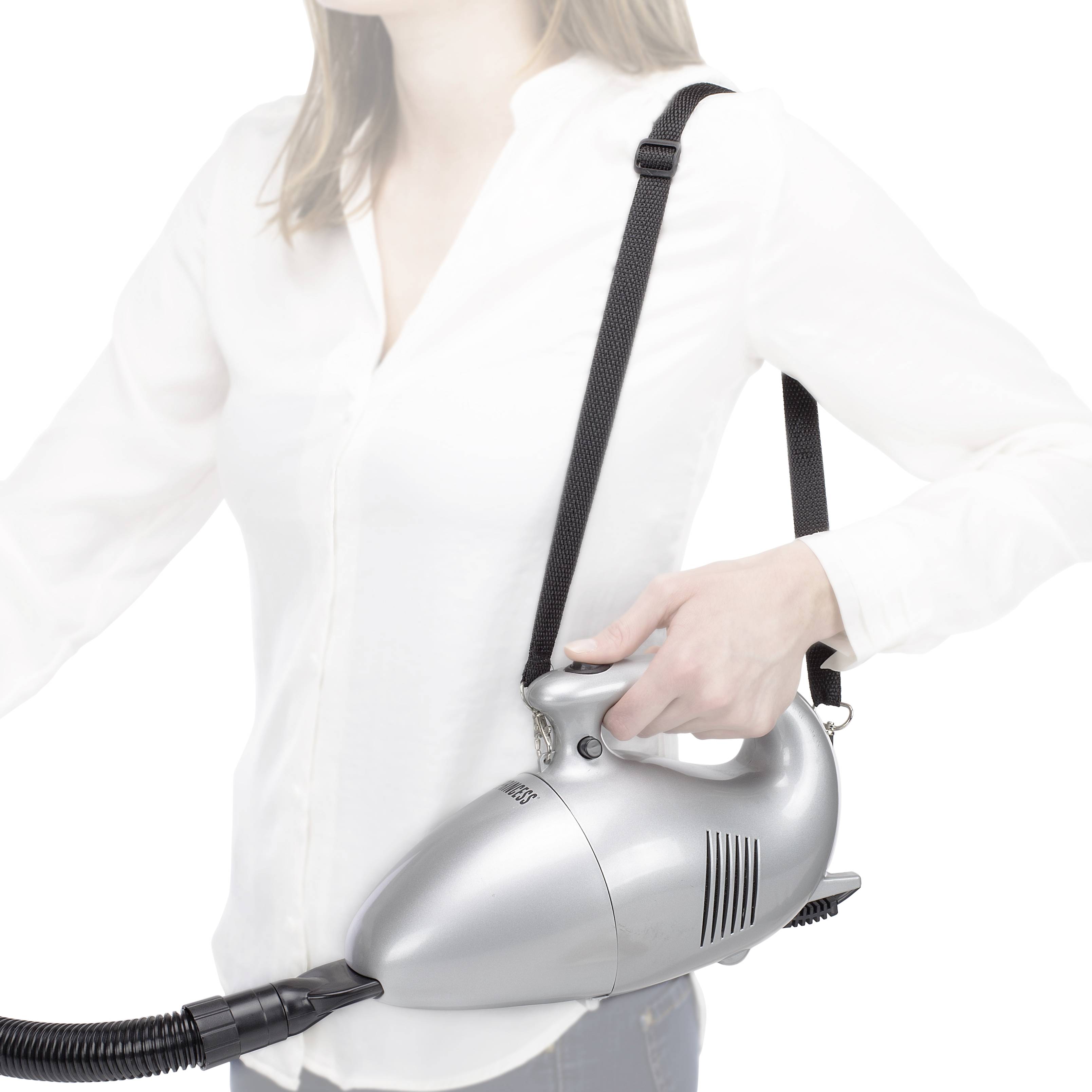 Eine Person bedient einen tragbaren Staubsauger. Der Staubsauger ist silbern und wird mit einem Riemen über der Schulter getragen.