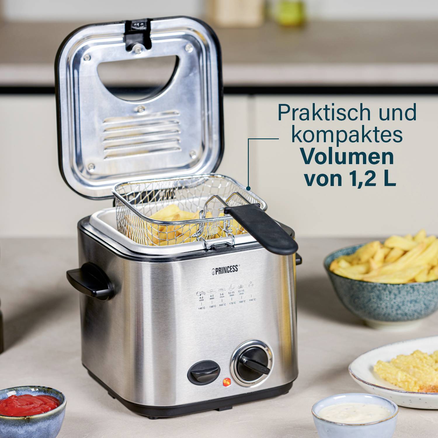 'Kleine Fritteuse auf Küchenarbeitsplatte, im Betrieb mit Pommes Frites. Text: Praktisch und kompaktes Volumen von 1,2 L.'