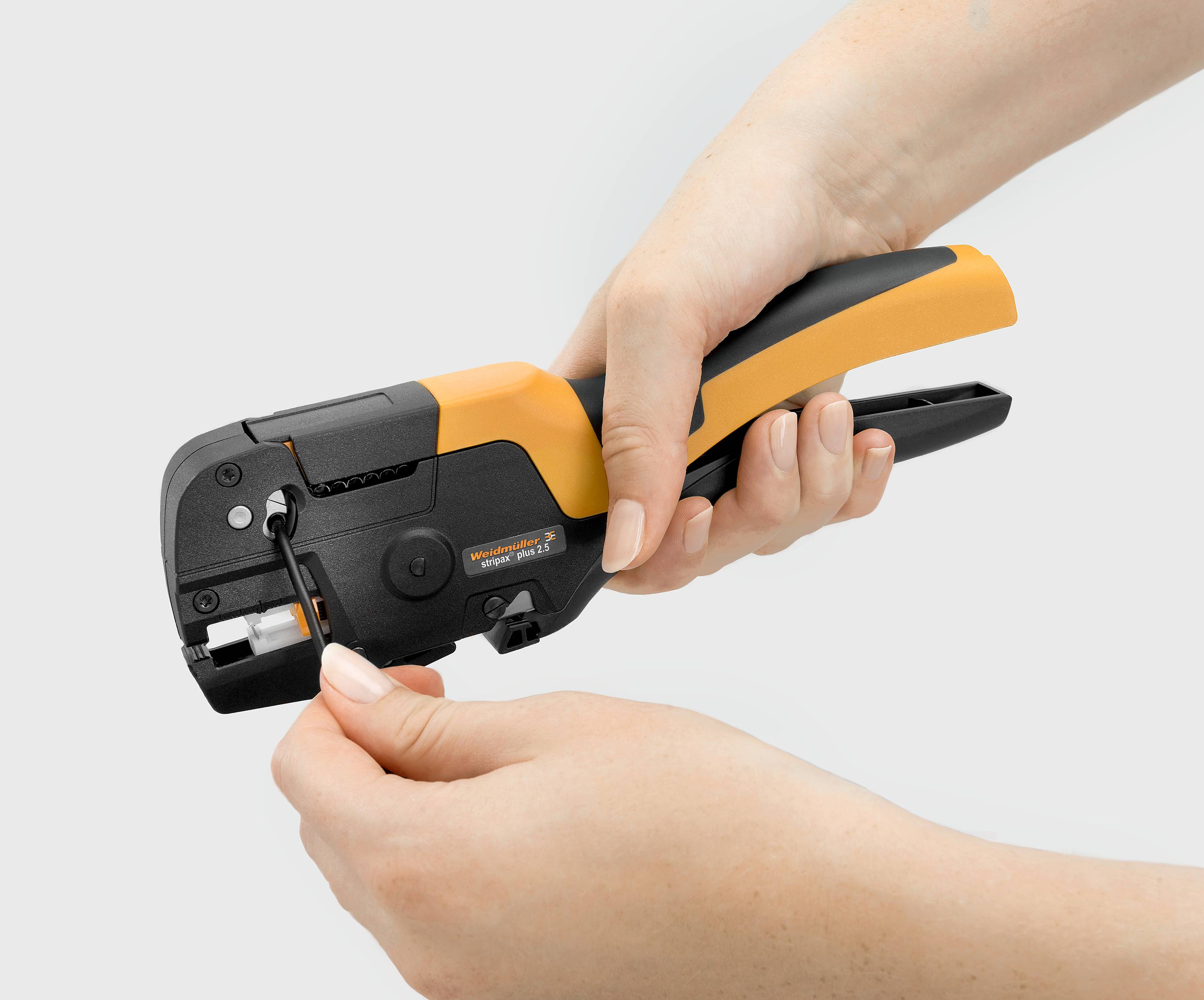 Person hält ein Crimpwerkzeug, das ein Kabel verbindet. Das Werkzeug hat einen orangenen und schwarzen Griff.