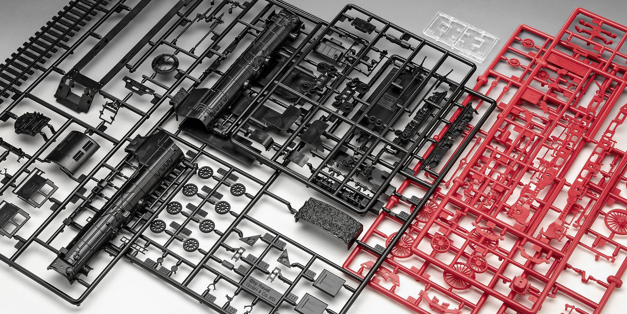 Plastikbausatz für Modelleisenbahnen mit schwarzen und roten Gitterrahmen, die Einzelteile für Lokomotiven enthalten.